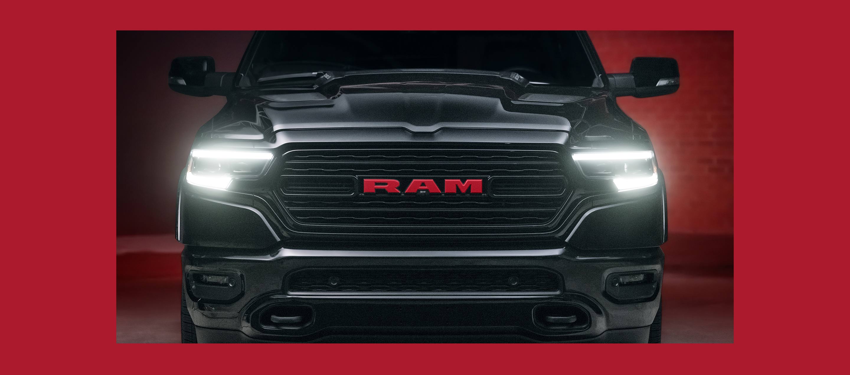 Primer plano de la parte delantar de una Ram 1500 Limited Ram Red Edition 2023 con sus faros delanteros encendidos.