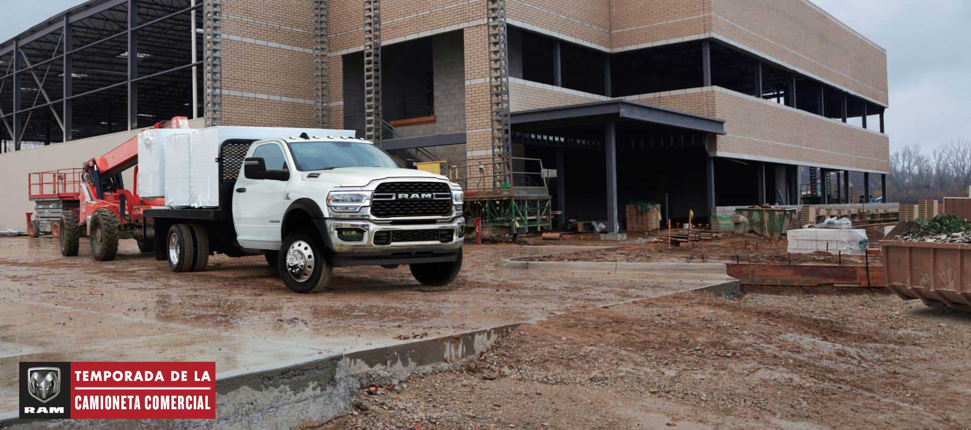 Una Ram Chassis Cab 2024 blanca con una mejora de plataforma cargada con materiales de construcción, estacionada en una obra de construcción comercial. Temporada de camionetas comerciales.