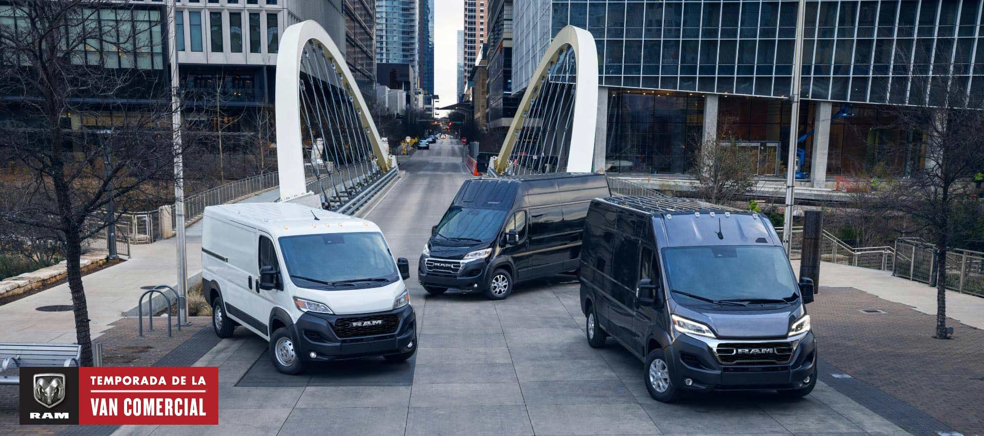 Tres modelos Ram ProMaster 2024, de izquierda a derecha: una Ram ProMaster 1500 Tradesman Standard Roof Cargo Van blanca, una Ram ProMaster 3500 SLT+ Super High Roof Cargo Van negra y una Ram ProMaster 3500 SLT High Roof Cargo Van negra, estacionadas en el centro de una gran ciudad ajetreada, con un puente de fondo. Temporada de vans comerciales.