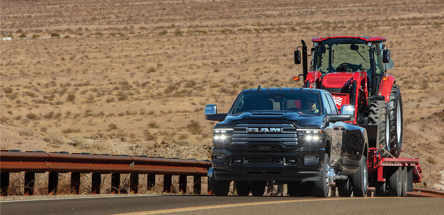 Una camioneta Ram acarreando maquinaria agrícola en un remolque.