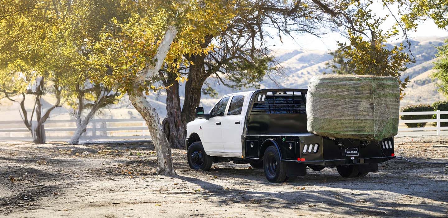 Una camioneta Ram Chassis Cab con un enorme fardo de heno cargado en la plataforma de carga.
