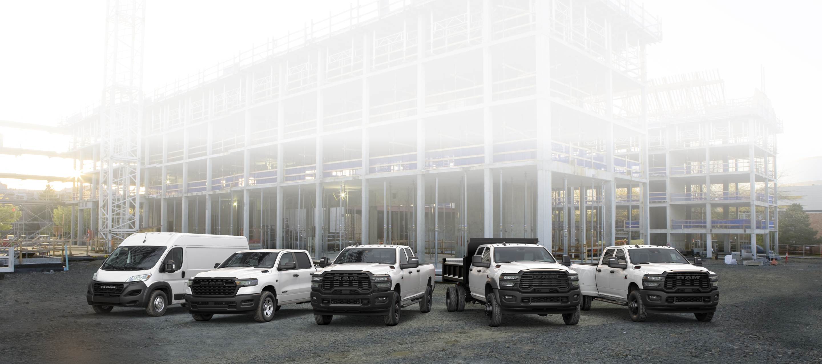 Una formación de camionetas y vans Ram 2026, todas de color blanco, en una obra comercial en construcción. De izquierda a derecha: una Ram ProMaster 3500 Tradesman High Roof Cargo Van, una Ram 1500 Tradesman 4x4 Crew Cab, una Ram 2500 Tradesman 4x4 Crew Cab, una Ram 3500 Tradesman Crew Cab Chassis Cab con una mejora de carrocería volcadora​​​​​​​ y una Ram 3500 Tradesman 4x4 Crew Cab.