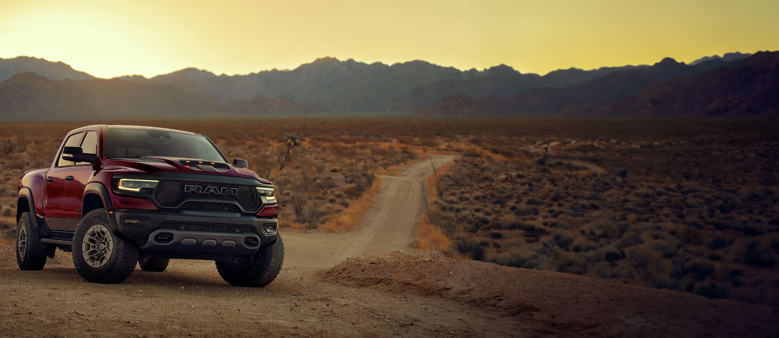 Una camioneta Ram 1500 TRX en un camino de tierra al atardecer.