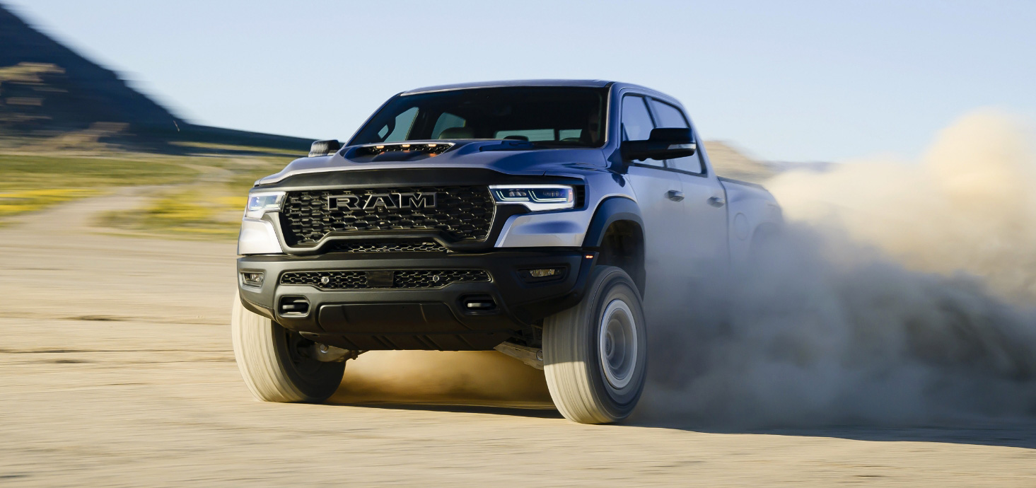 Una Ram 1500 RHO Crew Cab 2025 circulando todoterreno por el desierto, con el polvo y la arena que se desprenden de los neumáticos.
